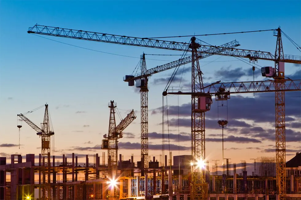 Tower cranes at a large construction site at dusk